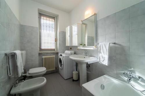 La salle de bains blanche est pourvue d'un lavabo et de toilettes. dans l'établissement Scarlet Apartment with Garden by Wonderful Italy, à Magreglio