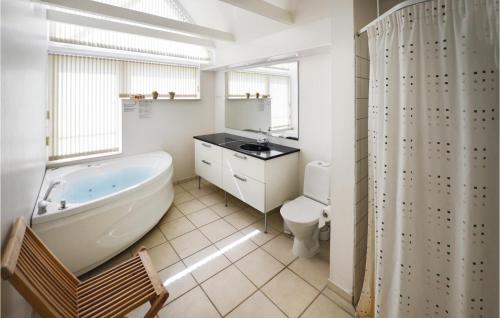 a bathroom with a tub and a toilet and a sink at Nice Home In Assens With Kitchen in Assens
