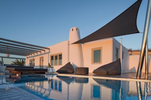 a house with a swimming pool in front of a house at Senses Luxury Houses in Fira