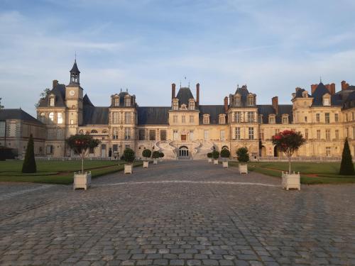 a large building with a brick driveway in front of it at Cœur de Fontainebleau: Confort, Calme & Haut débit in Fontainebleau