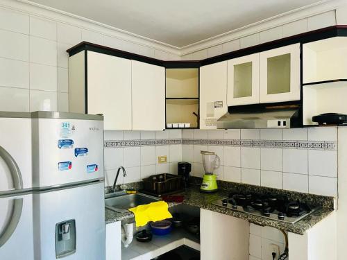 cocina con armarios blancos y nevera blanca en Santa Marta Apartamentos Salazar - Nuevo Rodadero, en Santa Marta