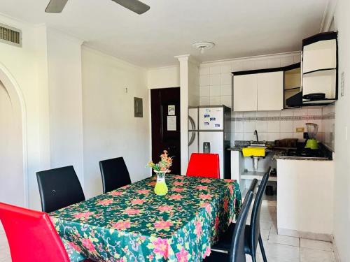 a dining room table with red chairs and a kitchen at Santa Marta Apartamentos Salazar - Nuevo Rodadero in Santa Marta