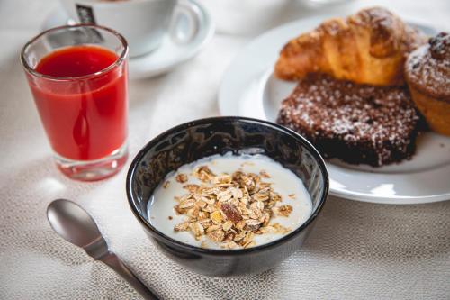 a table with a bowl of cereal and a plate of pastries at Hotel La Perla in Cervia