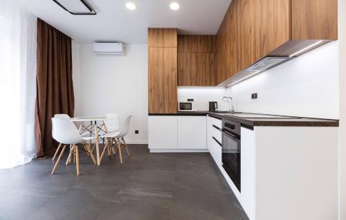 a kitchen with white cabinets and a table and chairs at Апартаменти на Кирилівська 37 in Kyiv