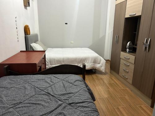 a bedroom with two beds and a desk and a dresser at Departamento interior 1er piso. in Cajamarca