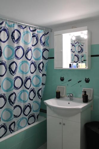Łazienka wyposażona jest w umywalkę oraz niebiesko-białą zasłonę prysznicową. w obiekcie Mona Hause w Atenach