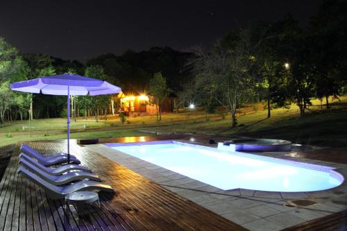 a swimming pool with two chairs and an umbrella at La Linda Cabañas in Dos de Mayo