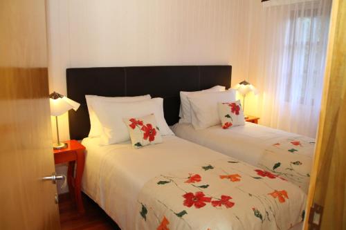 a bedroom with two beds with white sheets and red flowers at La Linda Cabañas in Dos de Mayo