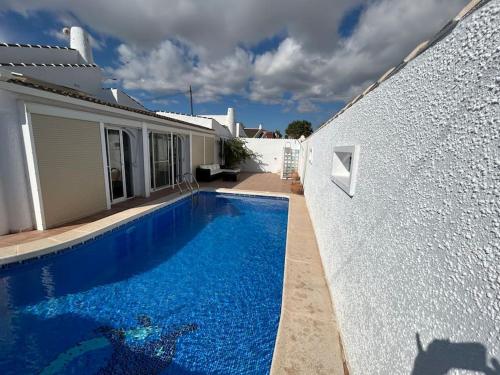 ロス・アルカサレスにある3 bed villa, large private pool 10 mins walk from beach and amenitiesの白い家の隣の青いスイミングプール