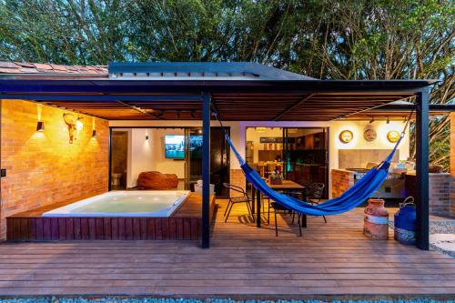 a hammock on a deck with a hot tub at Sweet Helen Llanogarden in Rionegro