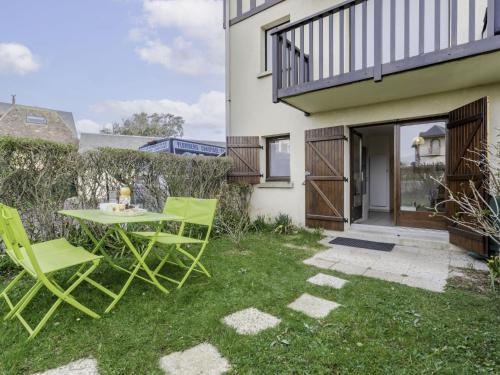 une terrasse avec des chaises vertes et une table en face d'une maison dans l'établissement Apartment Le Vert Clos by Interhome, à Villers-sur-Mer