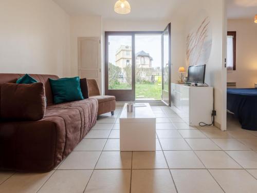 a living room with a couch and a tv at Apartment Le Vert Clos by Interhome in Villers-sur-Mer