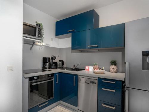 La cuisine est équipée de placards bleus et d'un réfrigérateur en acier inoxydable. dans l'établissement Apartment Les Flamants Roses-1 by Interhome, à La Grande Motte