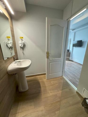 a bathroom with a sink and a mirror and a door at Pensiunea Korona in Miercurea-Ciuc