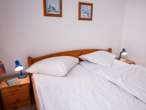 ein Bett mit weißer Bettwäsche und zwei Kissen darauf in der Unterkunft Apartment Küstennebel by Interhome in Norddeich