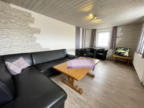 a living room with a black leather couch and a table at Holiday Home Martin by Interhome in Wald