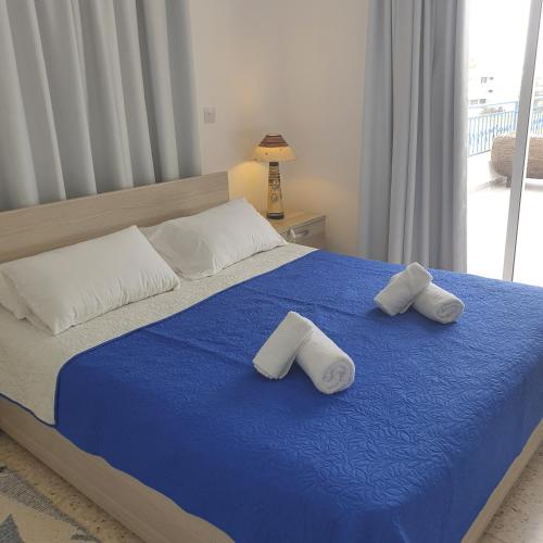 a bedroom with a blue bed with two towels on it at G&E Harbour Apartments in Lachi