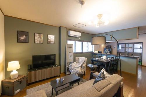 a living room with a couch and a dining room at It' ta de JPN - Self Check-In Only in Osaka