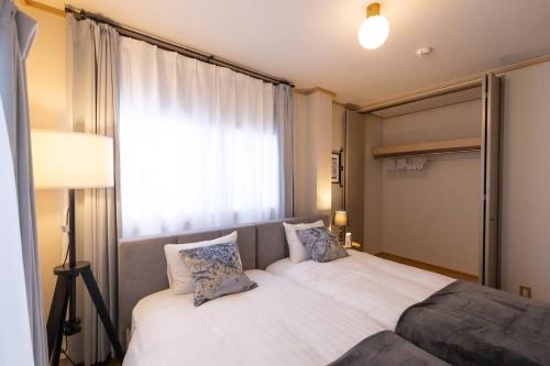 a bedroom with a large bed with a window at It' ta de JPN - Self Check-In Only in Osaka