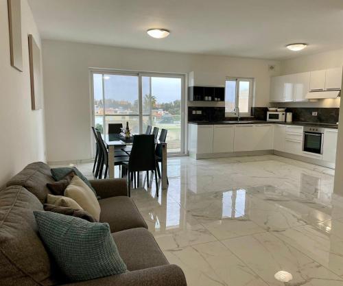 een woonkamer en een keuken met een bank en een tafel bij Spacious and Cozy Apartment near St Julians - Short Let Apartments Malta in Is-Swieqi