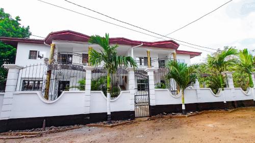 a white house with palm trees on the balcony at MICASO Guest House in Limbe