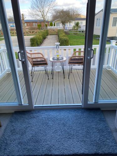 a screened porch with a table and two chairs at Cosy Holiday Home, Home Farm Holiday Park in Brent Knoll