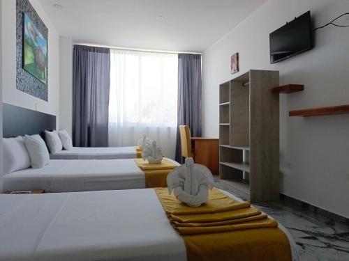 a hotel room with three beds and a television at Patty House Galapagos in Puerto Ayora