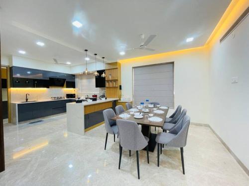 a dining room with a table and chairs and a kitchen at Ultra stylish 3bhk & home theatre room in Hyderabad