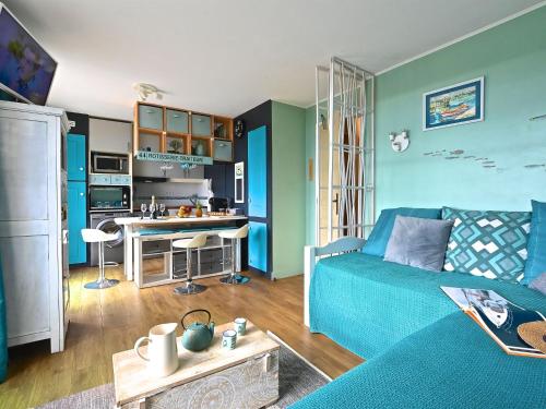 un salon avec un canapé bleu et une cuisine dans l'établissement Apartment Le Village - C4 323 by Interhome, à Agay
