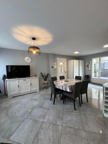 une salle à manger avec une table et des chaises et une télévision dans l'établissement Rez-de-chaussée de plain-pied avec parking privé au centre ville, à Dieppe