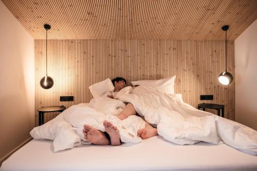 a man and woman laying in bed under blankets at Walser ART in Mittelberg
