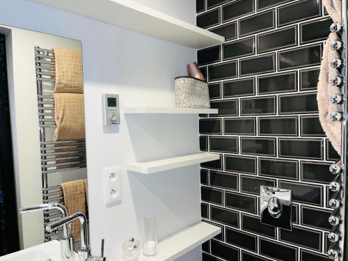 La salle de bains est pourvue de murs en carrelage noir et blanc et d'un lavabo. dans l'établissement Studio design Nuée bleue tout équipé centre ville, à Strasbourg