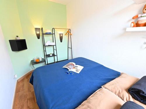 une chambre avec un lit bleu avec un livre dessus dans l'établissement Apartment Le Belvédère R4 320 by Interhome, à Saint-Raphaël