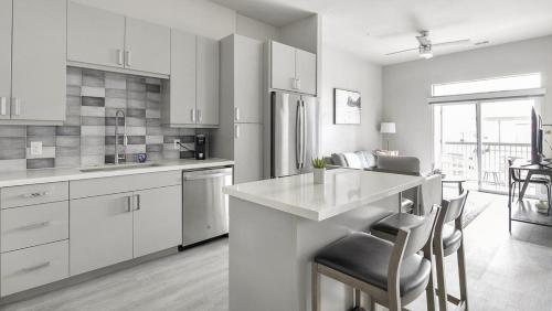 - une cuisine avec des placards blancs, une table et des chaises dans l'établissement Landing Modern Apartment with Amazing Amenities (ID1802X52), à Austin