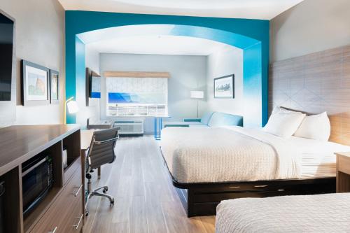 a hotel room with two beds and a desk at La Quinta by Wyndham Shawnee in Shawnee