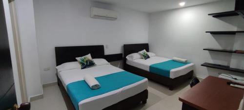 Habitación pequeña con 2 camas y escritorio. en Hotel Panama, en Neiva