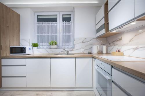 a white kitchen with a sink and a window at Apartamenty Pod Fortami in Przemyśl