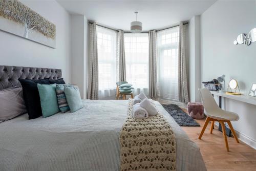 um quarto com uma cama grande e algumas janelas em Woodside Gardens Luxury Properties em Londres