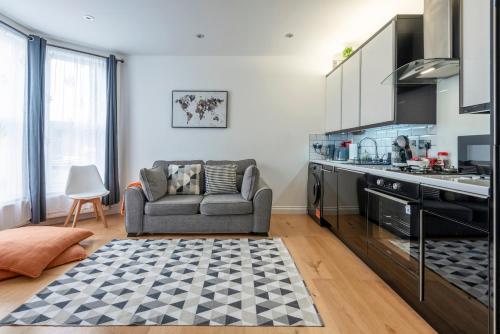 a living room with a couch and a kitchen at Woodside Gardens Luxury Properties near Alexandra Palace, Tottenham Stadium & Drumsheds in London