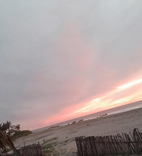 a sunset on a beach with a wooden fence at Tres Velas Surf in Celestino Gasca