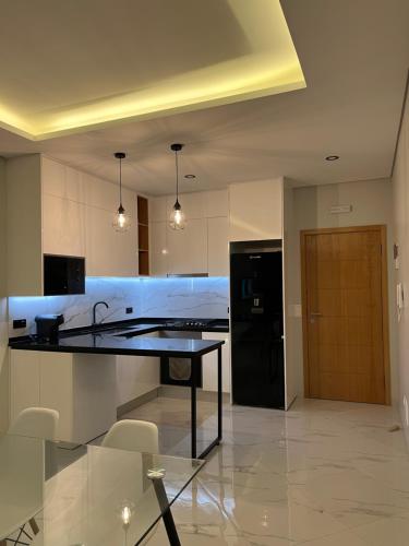 a kitchen with a table and a black refrigerator at Santos House Praia in Praia