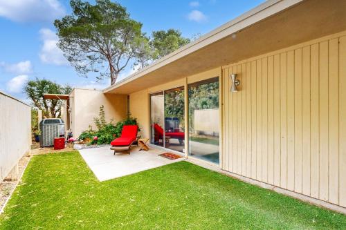 einen Hinterhof mit grünem Gras und roten Stühlen in der Unterkunft Racquet Club Cottage Permit# 271 in Palm Springs