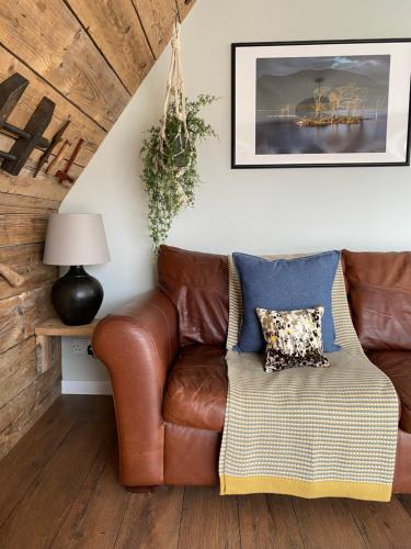 sala de estar con sofá de cuero marrón en Kylesku Lodges en Kylestrome