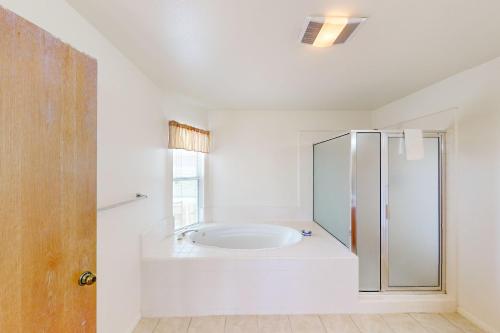 y baño blanco con ducha y bañera. en Ocean Mornings en Cayucos