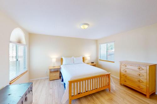 a bedroom with a bed and a dresser and two windows at Ocean Mornings in Cayucos