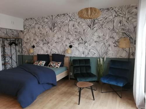um quarto com uma cama e duas cadeiras e um papel de parede em Studio neuf-Wintzenheim-proche Colmar-Parking em Wintzenheim