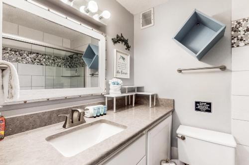 a bathroom with a sink and a mirror and a toilet at Top of the Gulf 708 in Panama City Beach