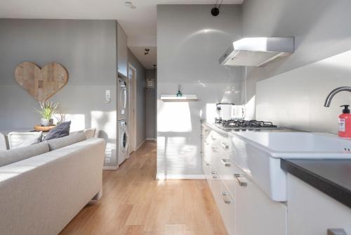 uma cozinha com balcões brancos e um sofá branco num quarto em 't Schelpje with free parking em Zandvoort