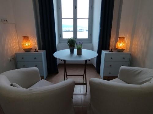 a living room with two chairs and a table and a window at Aegina Port Apt 4 in Aegina Town