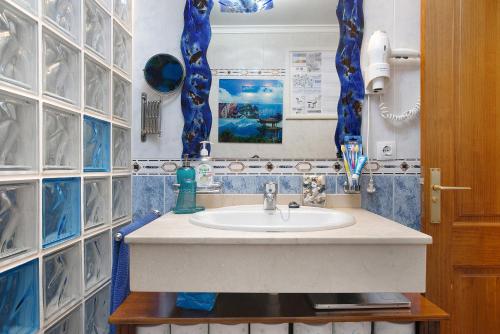 baño con lavabo y pared de azulejos azules en Casa Lancelot, en Tinajo